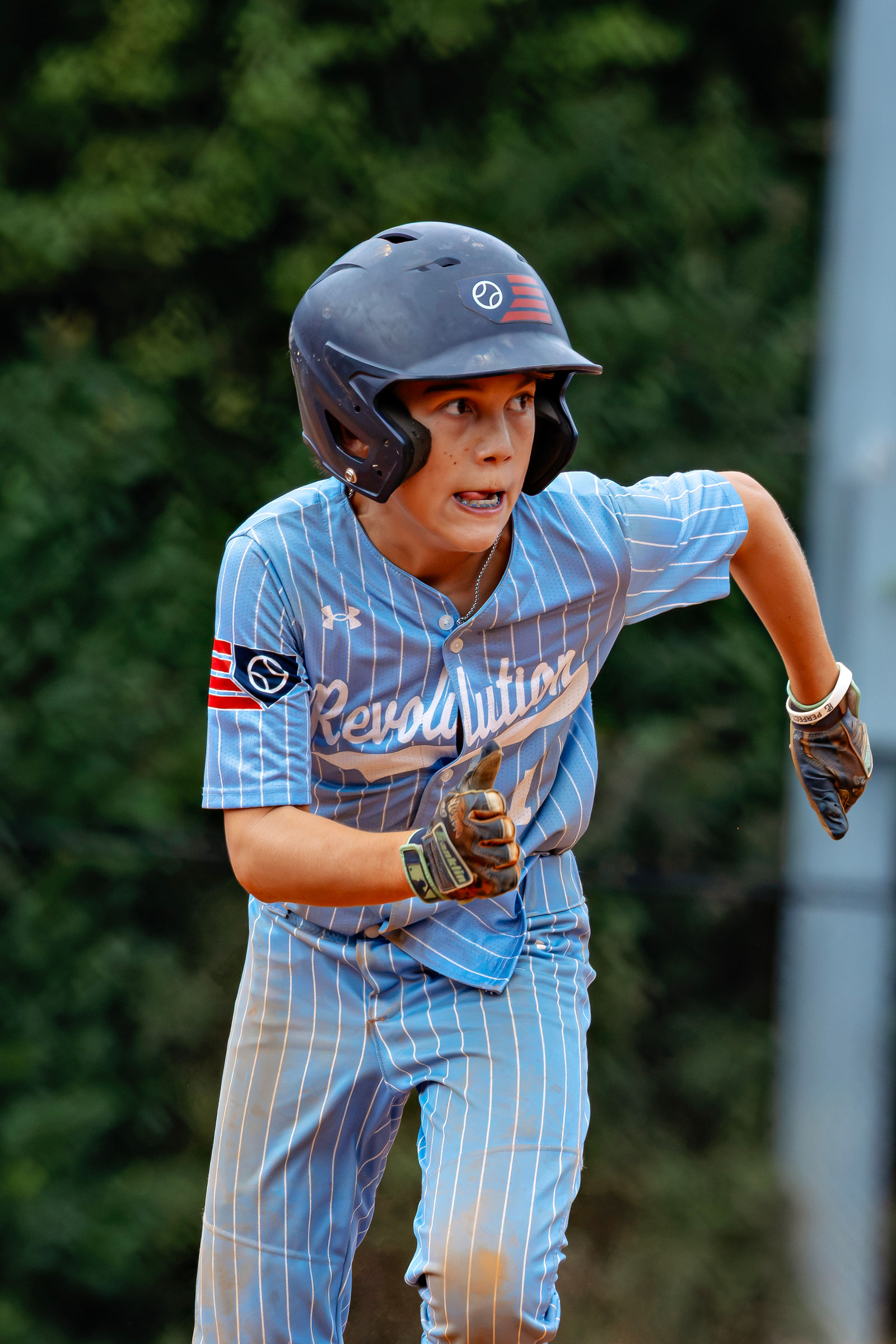 Cam Olson running the bases in his blue pinstripe Revolution uniform and batting helmet.
