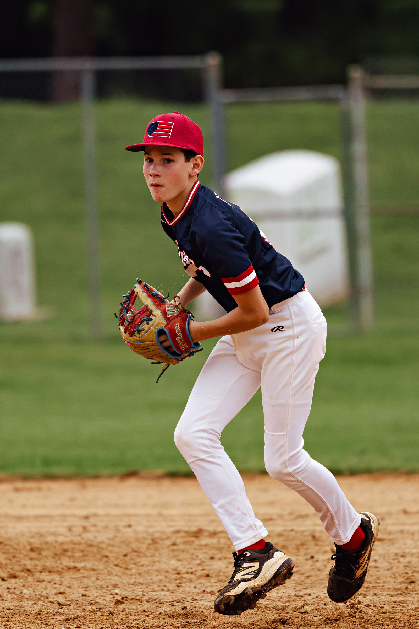 Eli Simpson fielding in a navy Revolution jersey and red cap.