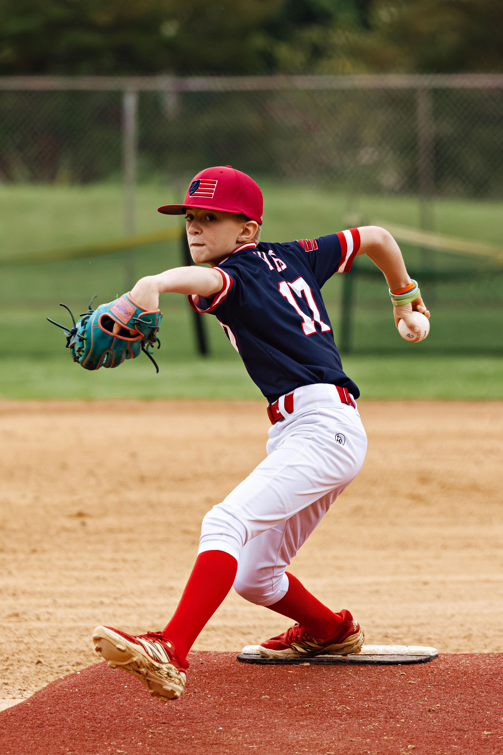 Mason Ward pitching in a navy Revolution jersey and red cap.